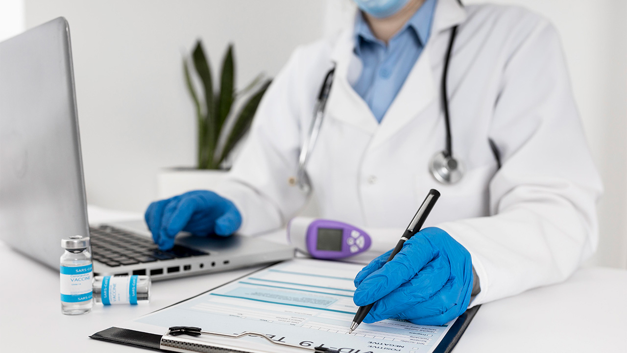 A doctor filling out a form and looking at the computer 