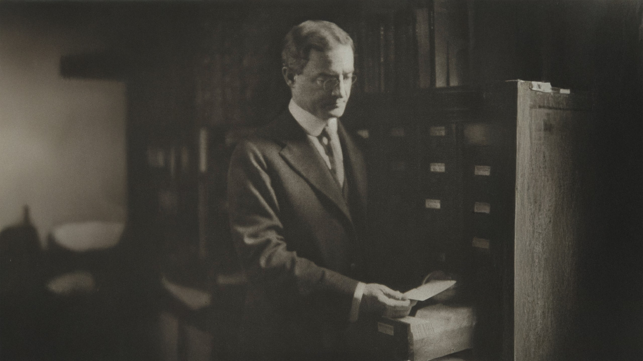 William J. Gies, a renowned journalist in his time, looking at a letter in his library
