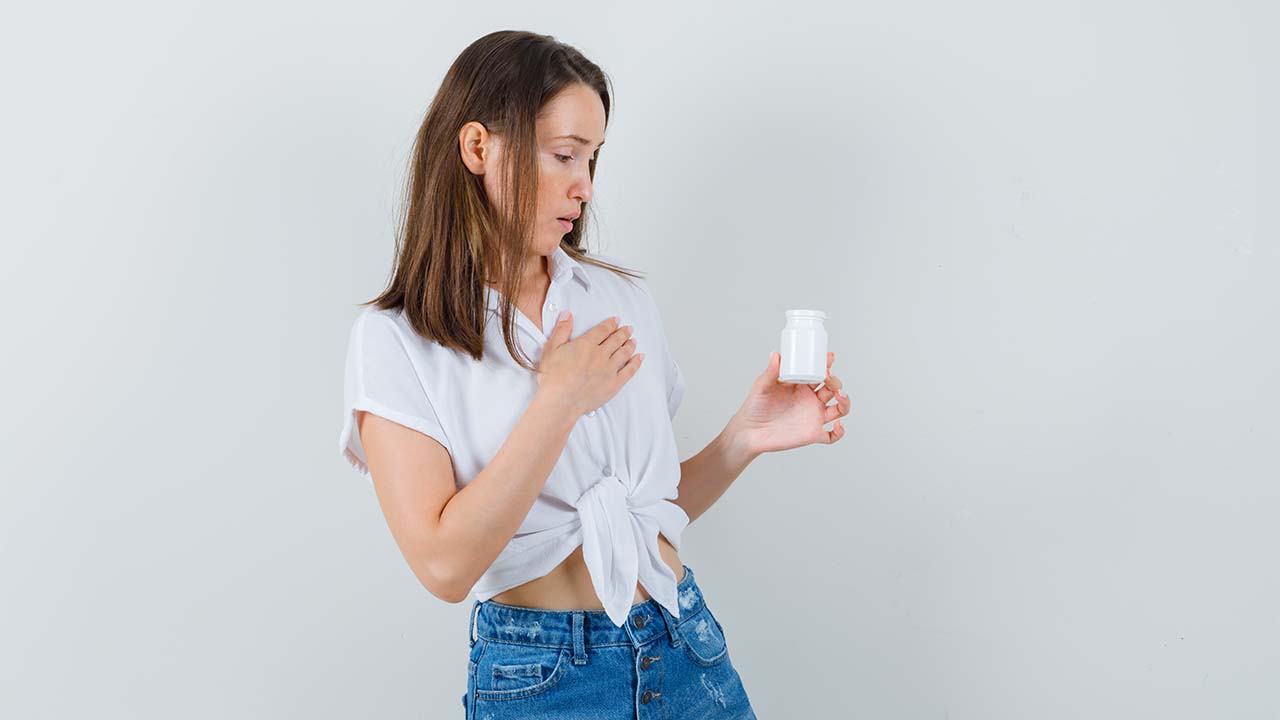 A lady looking at a white container in her hand filled with home remedies