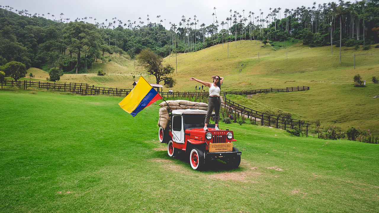 Una mujer posa sobre un Jeep Willys en el Valle de Cocora